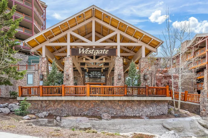 Spacious covered entry with exposed wood beam ceiling, stone pillars, and wood railing