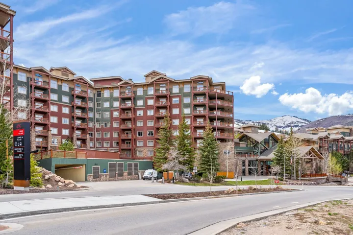Multi-story residential building featuring a stone and wood exterior with multiple balconies