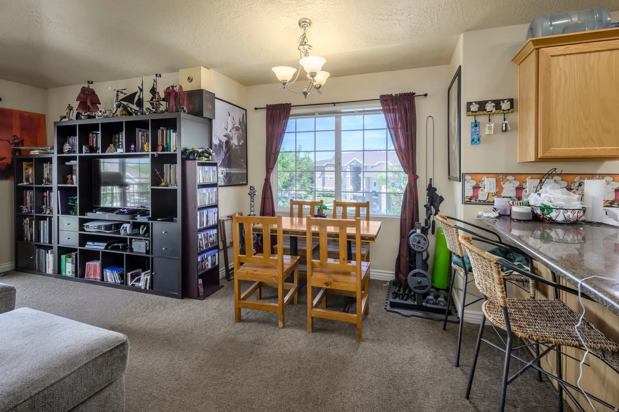 Open-concept living area with neutral carpeting and a large window providing ambient light