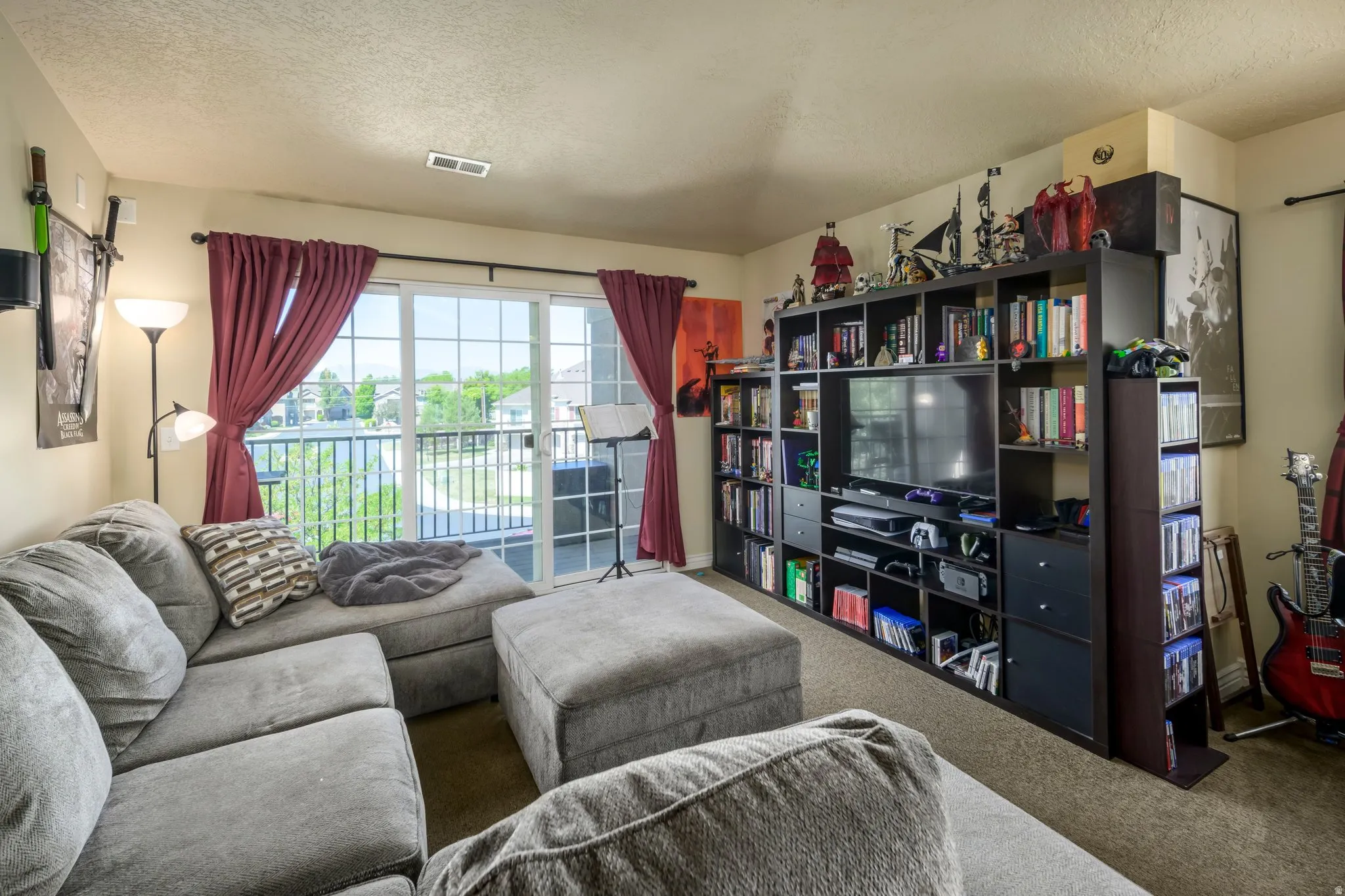 Living space featuring a sliding glass door, balcony with metal railings, built-in shelving unit, and wall-to-wall carpeting