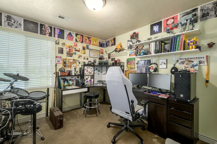 Spacious room featuring broad window blinds, a built-in corner desk with storage, and integrated shelving