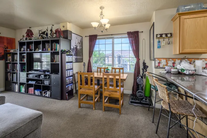 Open-concept living area with neutral carpeting and a large window providing ambient light