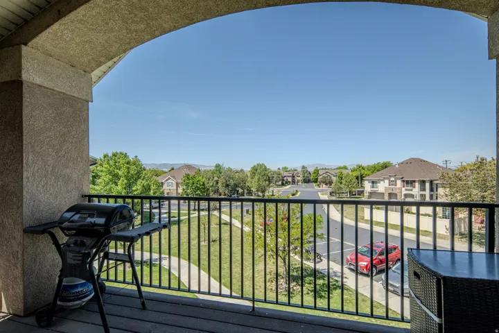 Spacious private balcony featuring a textured stucco archway, black metal railings, and wood-finish decking