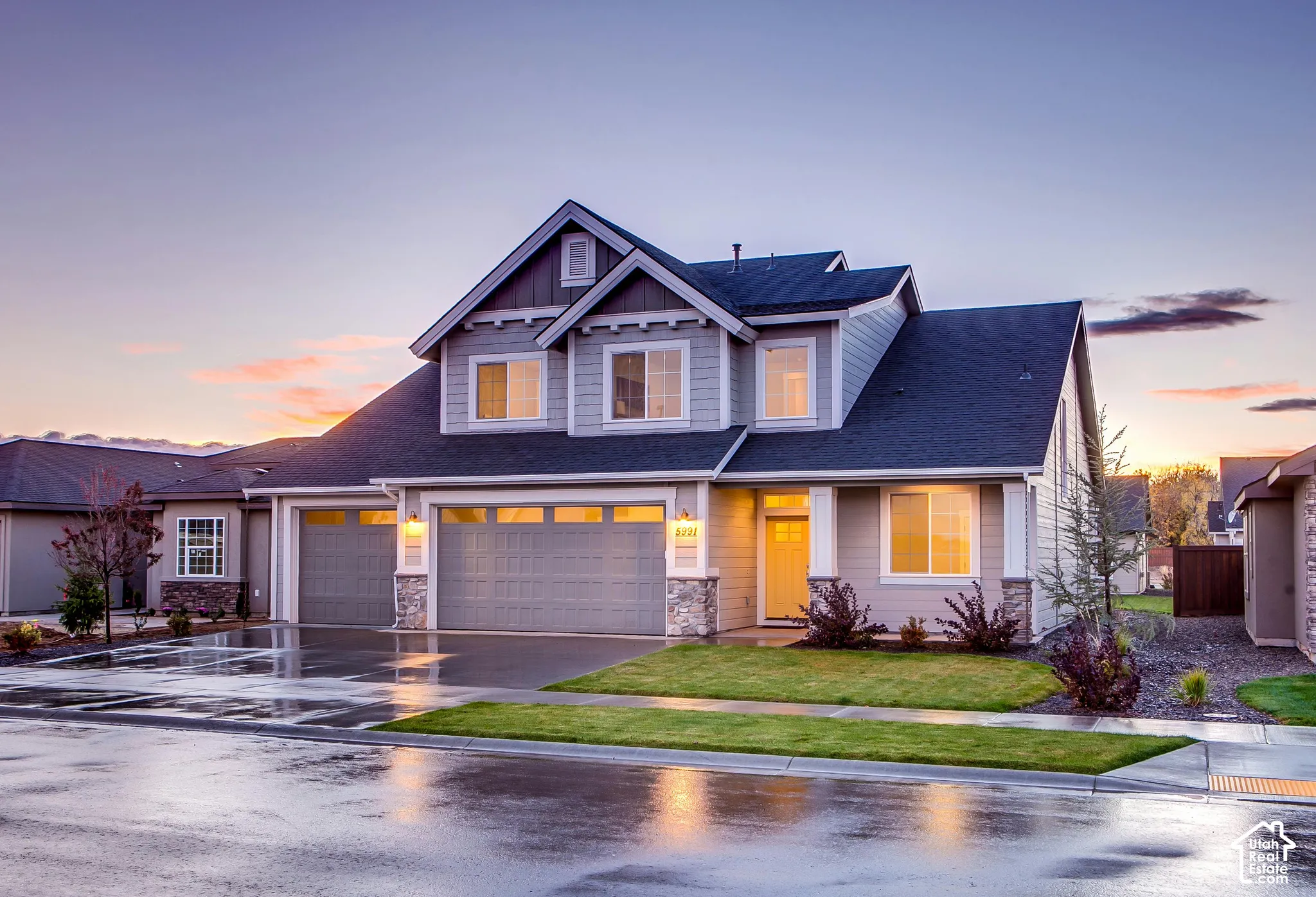 Two-story residence featuring horizontal lap siding, stone veneer accents, a multi-gable roofline, a three-car garage, and a covered front entryway