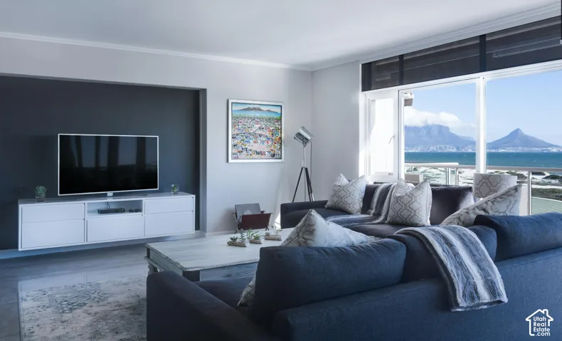 Living area featuring floor-to-ceiling windows, mountain and coastal scenery, a matte black accent wall, and a custom white wall-mounted media cabinet