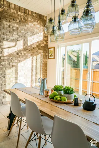 Exposed brick feature wall, cluster pendant lighting with glass shades, sliding glass patio door, and stone-finish flooring