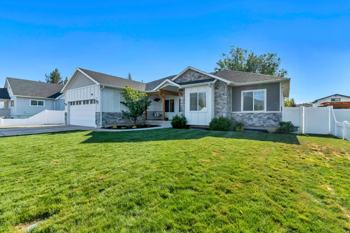 Contemporary exterior featuring light gray siding with stone accents and a white picket fence