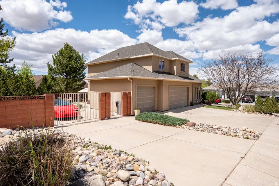 Stucco exterior residence featuring a two-car garage, concrete driveway, and a gated side yard