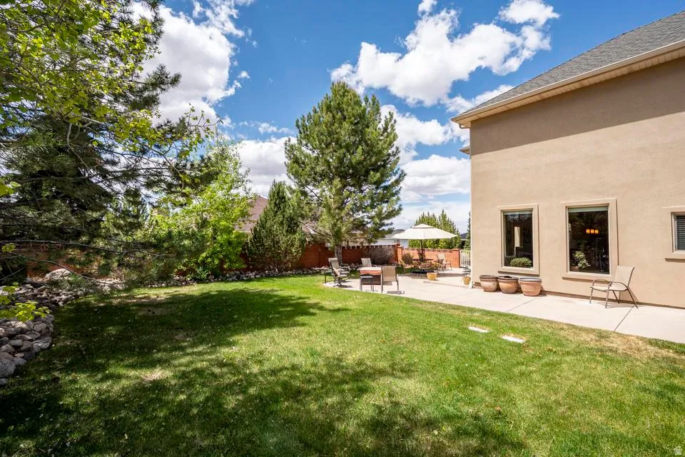 Expansive rear yard featuring a manicured lawn, established landscaping, and a substantial patio area