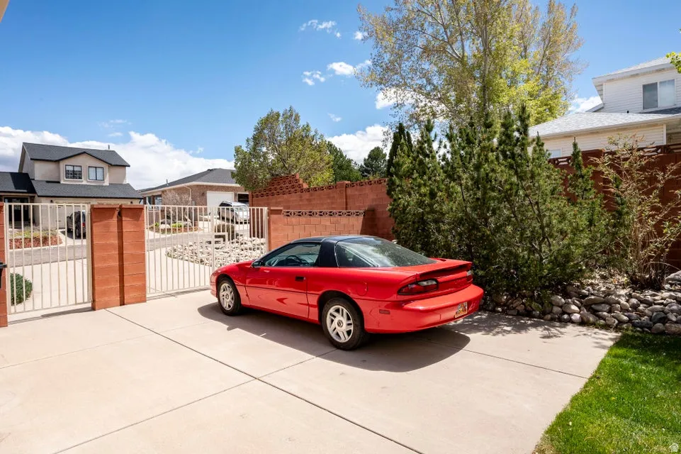 Paved driveway with a double white metal gate and brick pillars