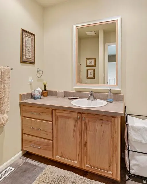 Spacious vanity featuring a light wood cabinet with three drawers and two cabinet doors, a large countertop, and an integrated white sink with chrome fixtures
