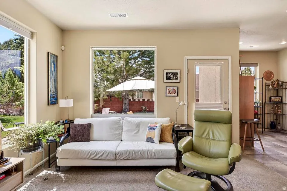 Living area featuring large windows, neutral-toned walls, and a glass-paneled exterior door