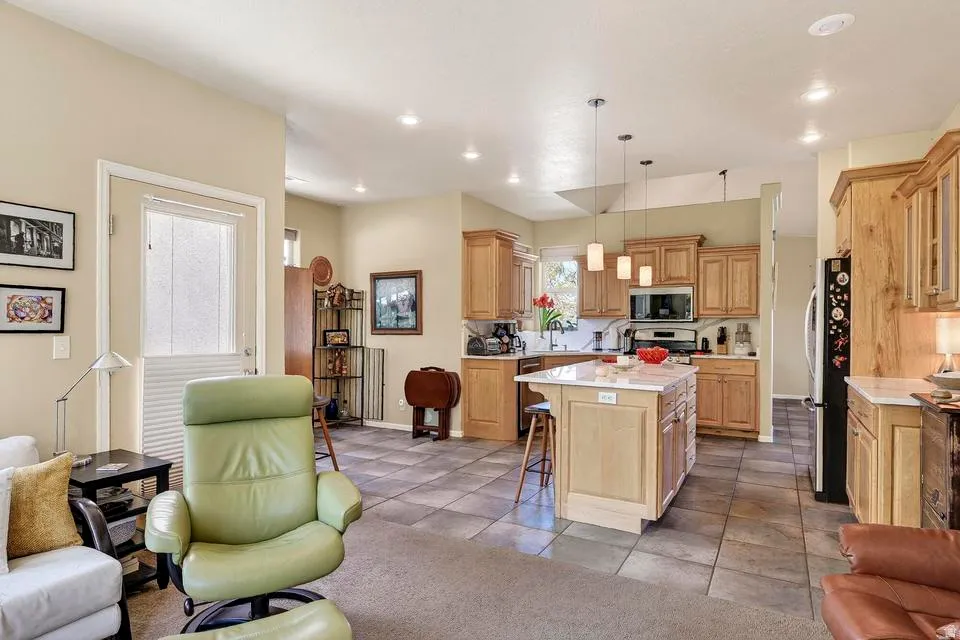 Open-concept kitchen featuring light wood cabinetry, a central island with a light-colored countertop, and stainless steel appliances