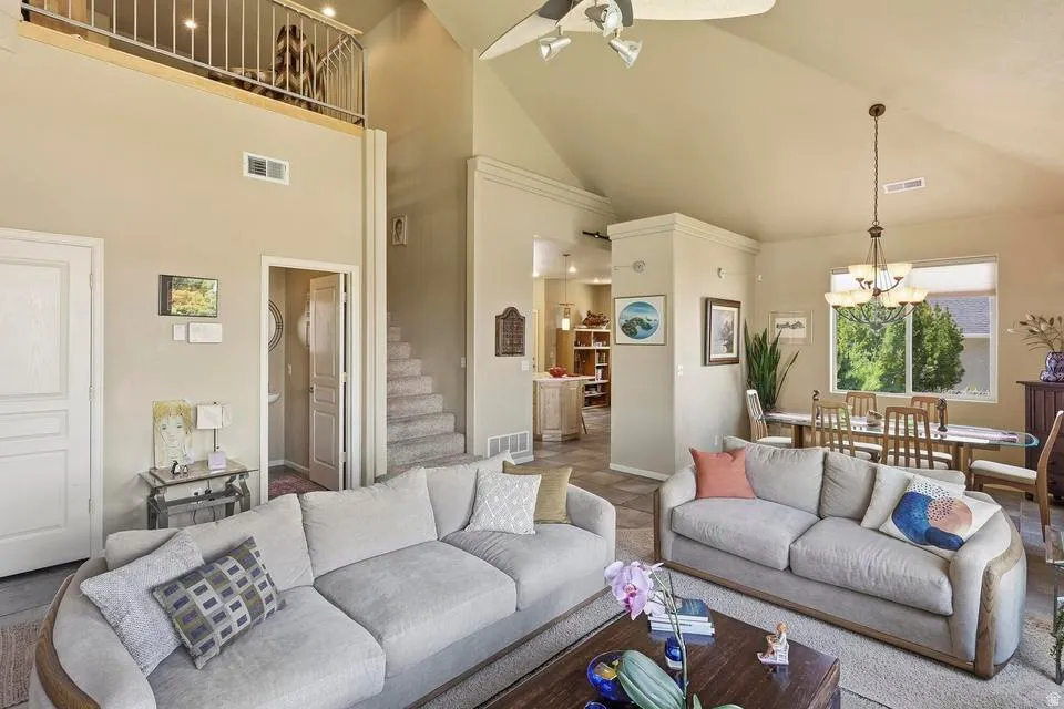 Vaulted ceiling living area with a loft overhead, featuring a staircase with carpeted treads
