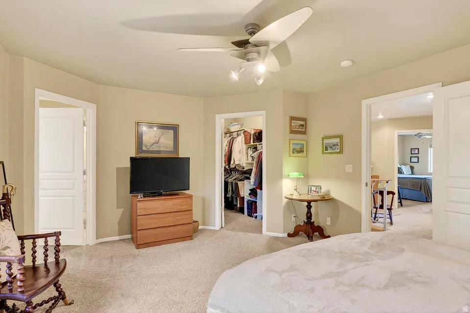 Carpeted room featuring a ceiling fan with integrated lighting, recessed lighting, and a walk-in closet with built-in shelving