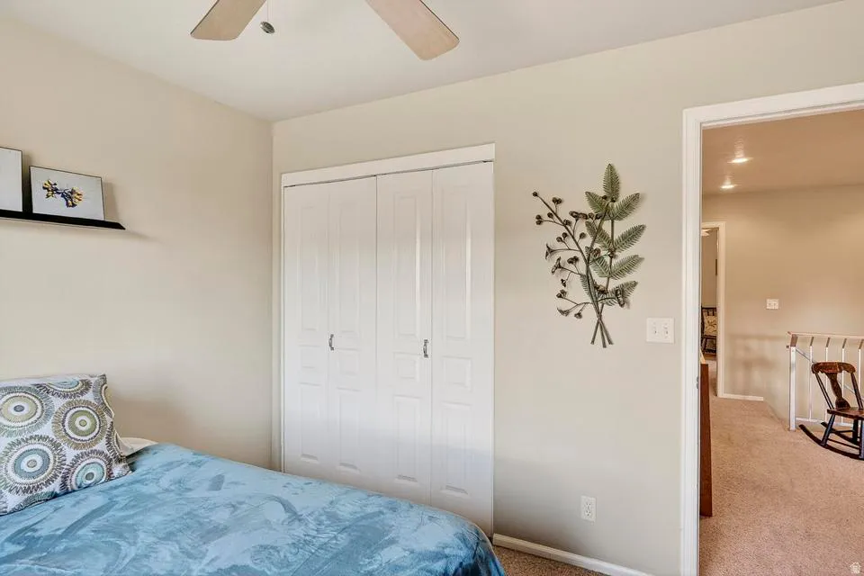 Room with neutral-toned walls, a ceiling fan, and white bi-fold closet doors