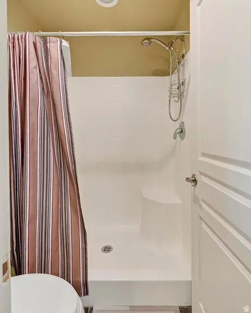 Shower enclosure featuring a built-in bench, handheld showerhead, and white subway tile-patterned surround
