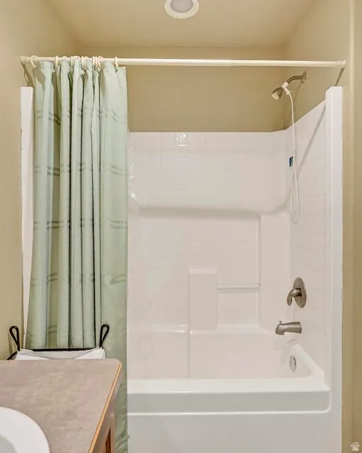White porcelain bathtub with integrated shower, featuring a brushed nickel shower head and faucet