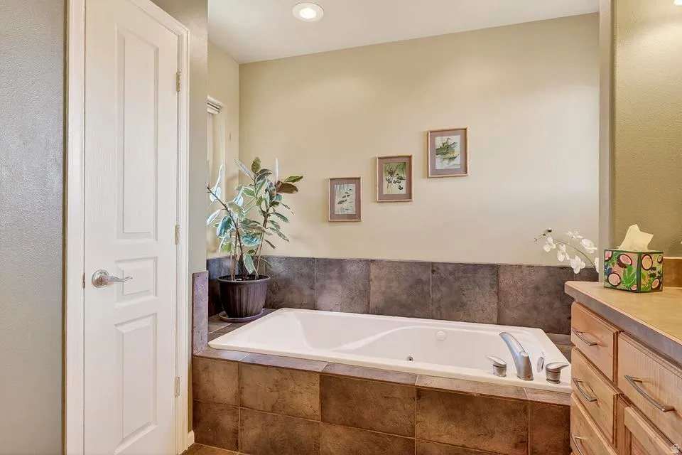 Built-in soaking tub with a tiled surround, brushed nickel fixtures, and recessed lighting