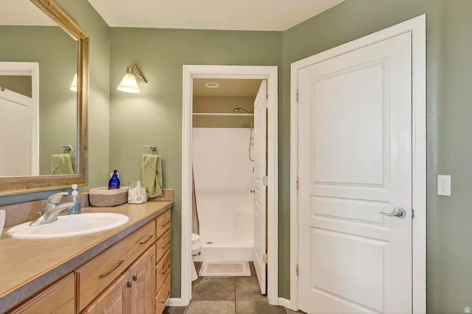 Bathroom featuring a wood-finish vanity with a single sink, an expansive countertop, and an overhead vanity light