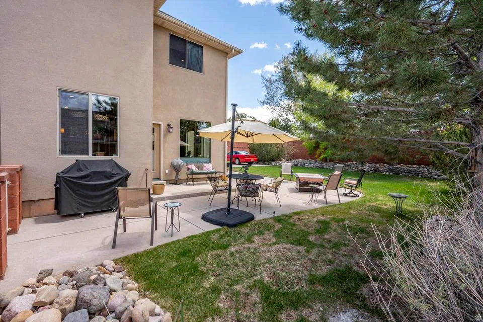 Expansive concrete patio with direct access to the rear facade, surrounded by a manicured lawn and mature landscaping