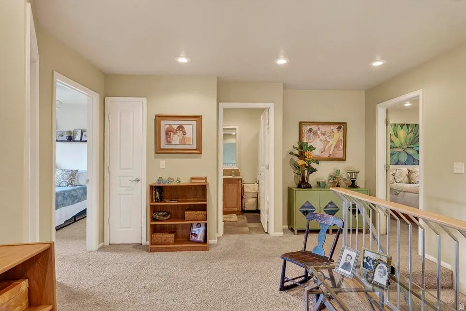 Carpeted hallway featuring recessed lighting, white interior doors, and a wood and metal railing