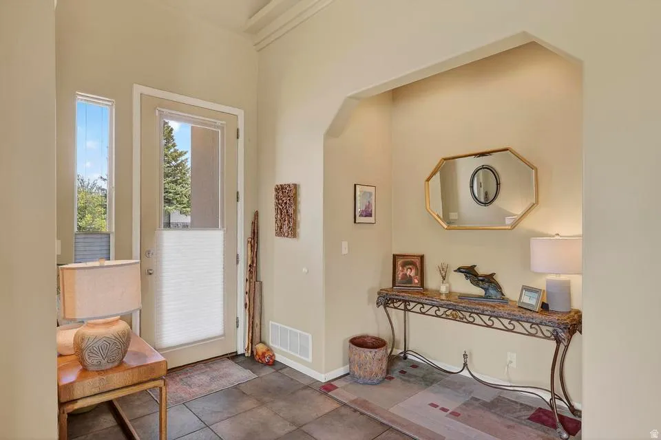 Entryway featuring tile flooring, a full-light entry door, sidelight window, and an architectural archway
