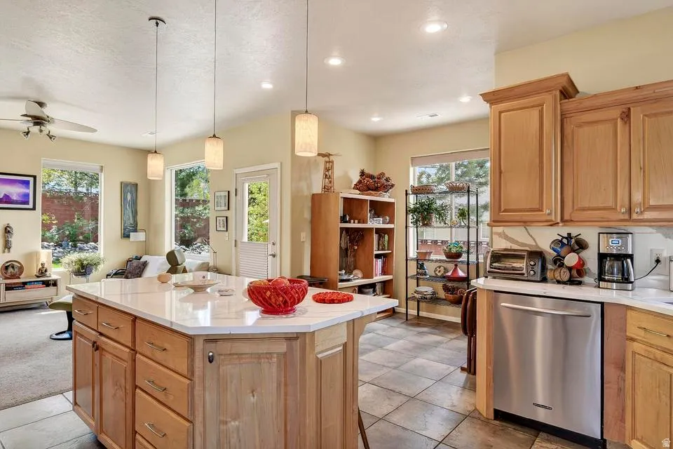 Kitchen featuring a central island with natural wood cabinetry, light-toned countertop, and pendant lighting