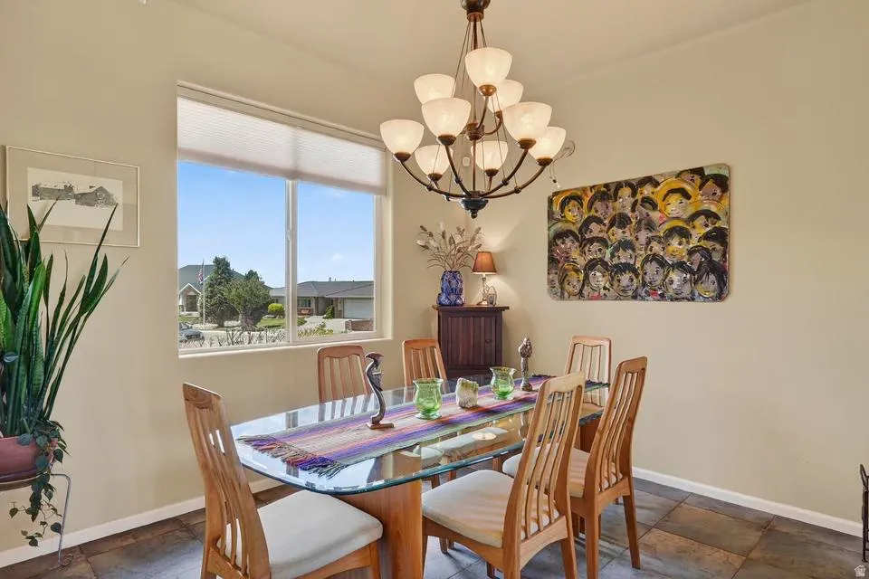 Dining area featuring a prominent window, a multi-arm chandelier, and tile flooring