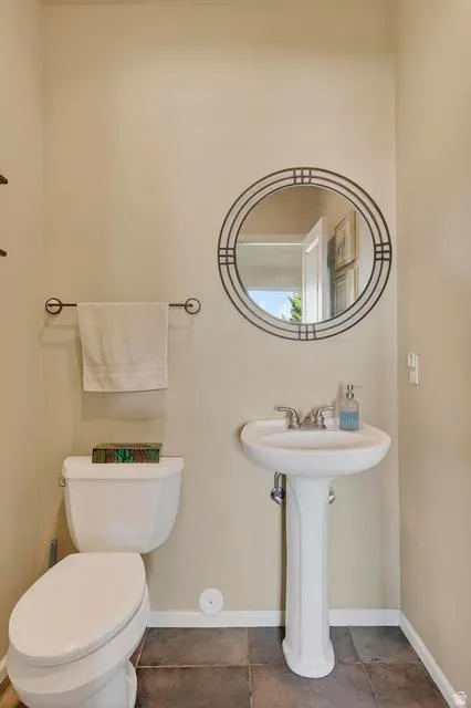 Pedestal sink with chrome fixtures, a round decorative mirror, and neutral wall tones