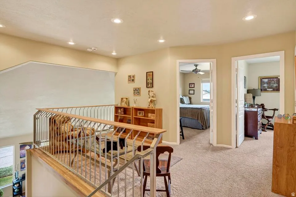 Upper-level landing featuring recessed lighting, light-toned carpeting, and a wood-finish and metal railing overlooking a lower space