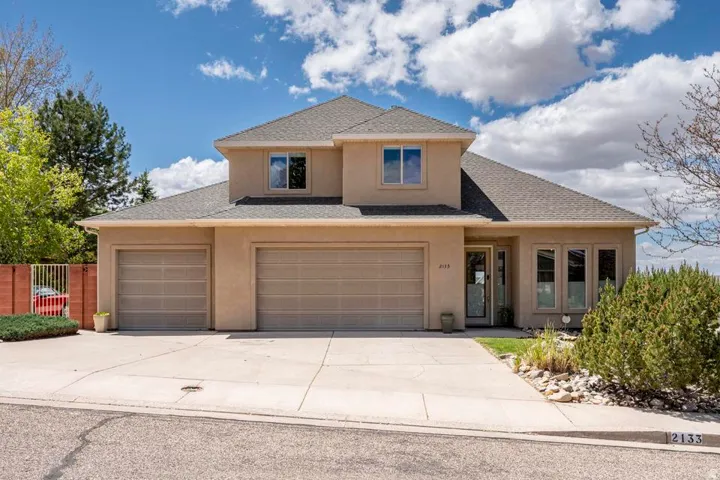 Stucco exterior residence featuring a multi-level design, a two-car garage with individual doors, a concrete driveway, and a front entry with a glass-paneled door