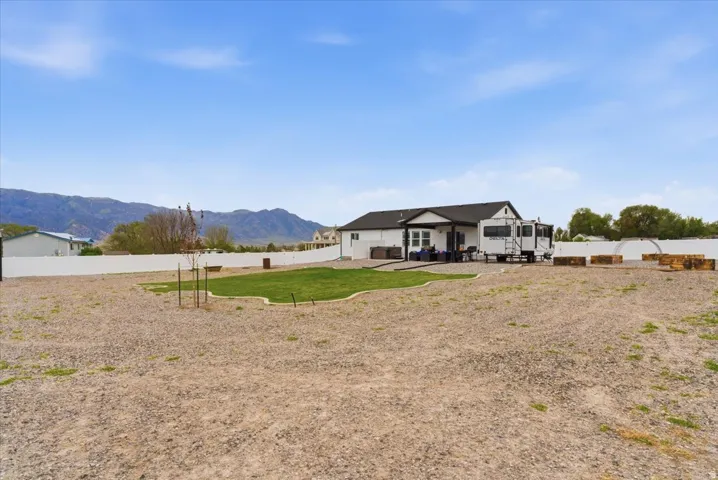 Expansive gravel lot featuring a central grass area, mountains, and a white vinyl fence