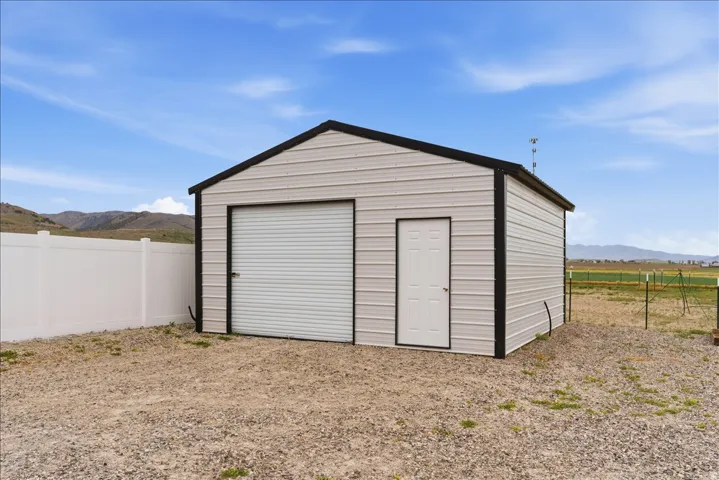 Metal utility building featuring a roll-up garage door and a side entry door