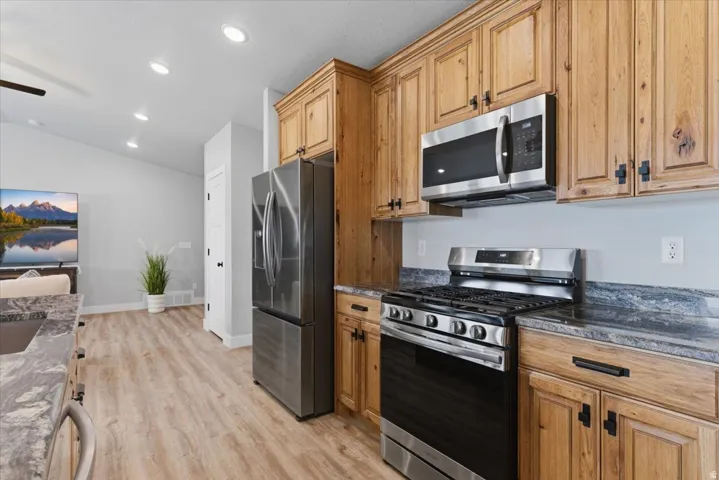 Kitchen featuring wood cabinetry, stainless steel appliances including a refrigerator, range, and microwave, and stone-look countertops