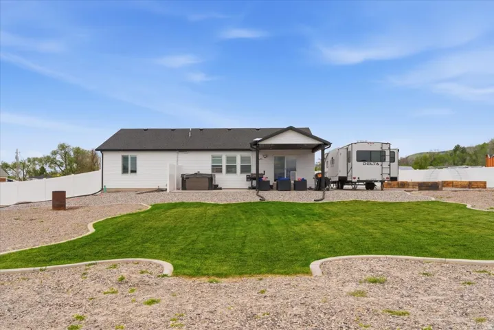 Manicured lawn with gravel landscaping and a white privacy fence