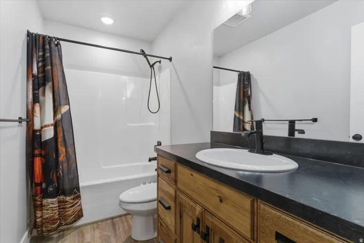 Bathroom featuring a wood-finish vanity with a dark countertop and oval sink