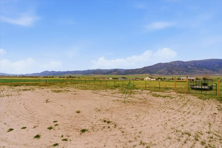 Expansive undeveloped land featuring a partial perimeter fence and distant mountain scenery