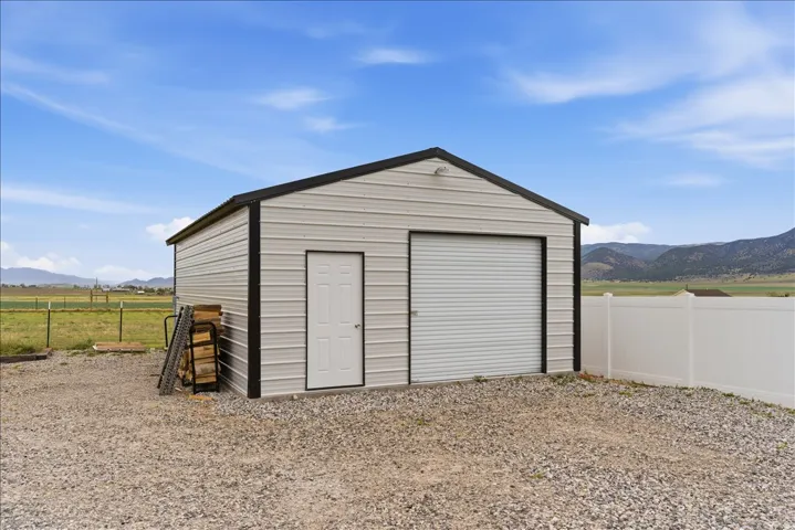 Detached metal utility building featuring a roll-up garage door and a side entry door