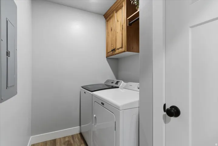 Dedicated laundry space featuring wood-finish flooring, white baseboards, and light gray walls