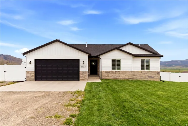 Ranch-style residence featuring a dark asphalt shingle roof, white horizontal siding, and a stone veneer foundation