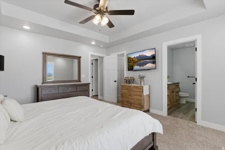 Spacious bedroom featuring a tray ceiling, recessed lighting, and a ceiling fan