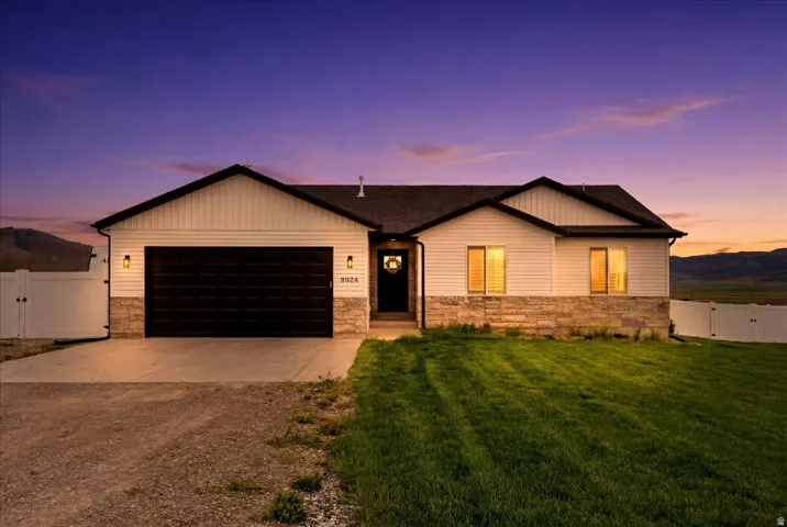 Contemporary ranch-style residence featuring white horizontal siding and a stacked stone facade