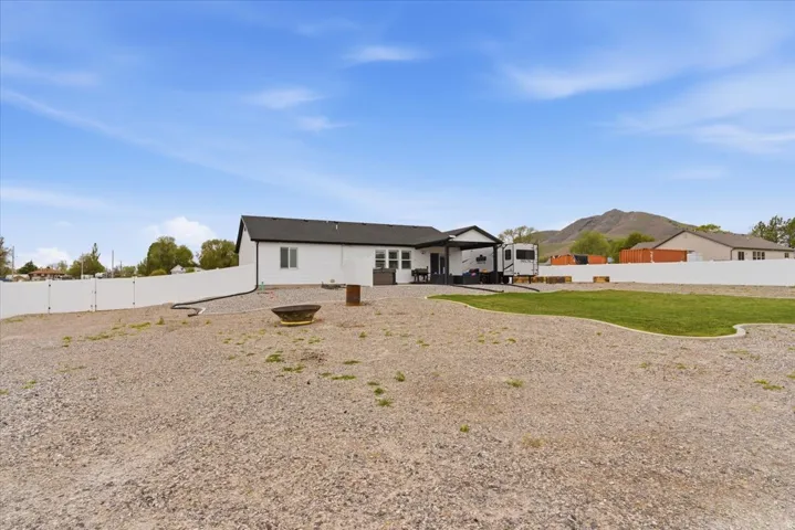 Spacious backyard featuring a gravel landscape, a dedicated grass area, and a fire pit