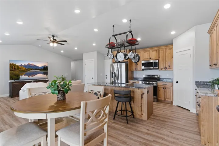 Open-concept living space featuring wood-finish flooring, recessed lighting, and a vaulted ceiling