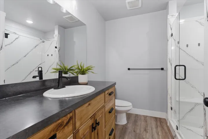 Modern bathroom featuring a wood-finish vanity with an oval undermount sink and matte black faucet