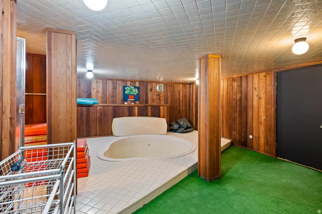 Indoor spa area featuring wood paneling, a built-in spa with tiled surround, and a sauna with a glass door