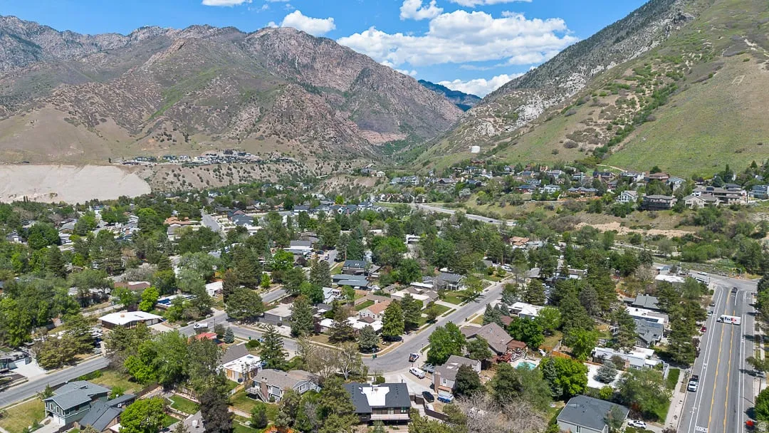 Mountainous landscape framing a residential neighborhood with mature trees, established homes, and a prominent roadway