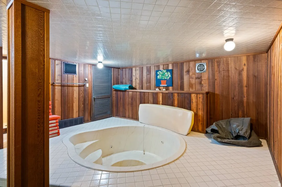 Recessed soaking tub set into a white tiled floor, complemented by wood paneling on the walls