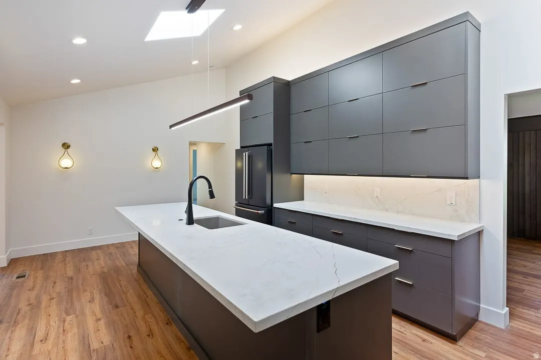 Kitchen featuring a large center island with a sink, white countertop, and a matte black faucet